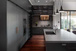 Modern dark kitchen with sleek cabinets, central island, and pendant lighting.