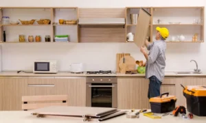 man removing kitchen cabinet door with tools on counter showing cabinet repair or replacement process